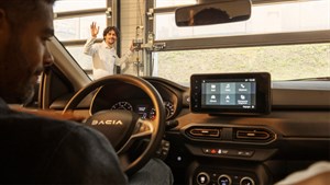 Pogled iz unutrašnjosti vozila Dacia prema muškarcu koji maše ispred garaže.








