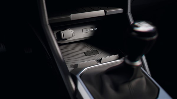 Središnji dio unutrašnjosti vozila Dacia s prikazom ručnog mjenjača, USB-C priključka, 12V utičnice i bežične površine za punjenje.
