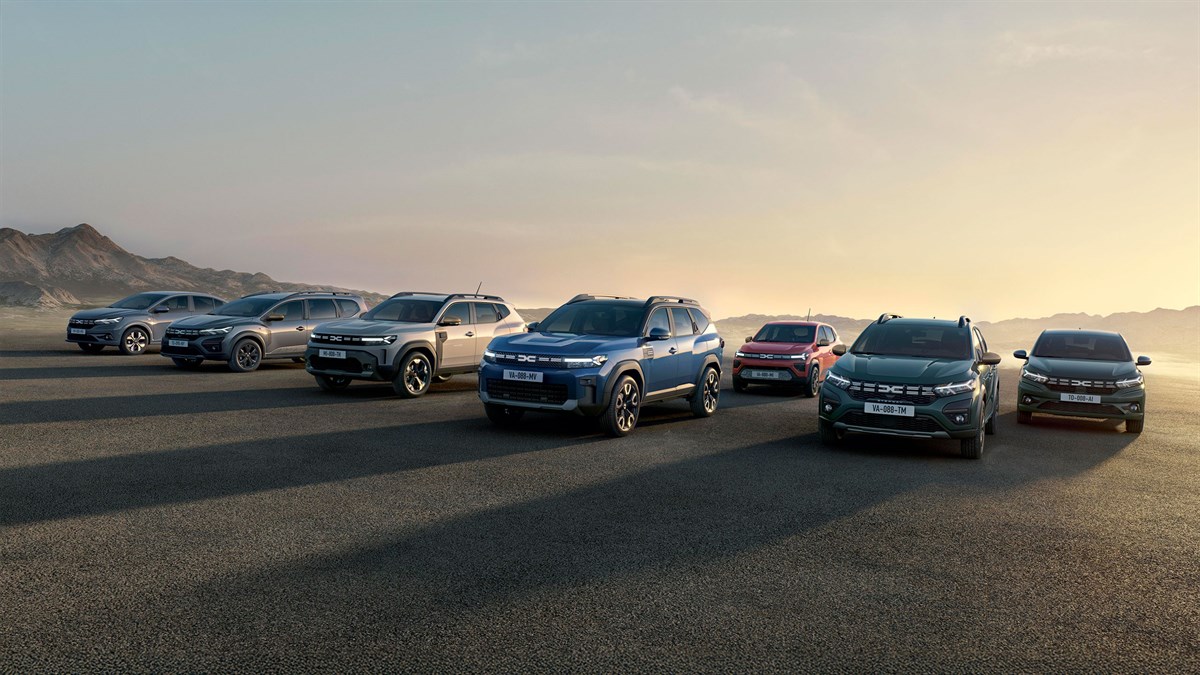 Linija vozila Dacia parkiranih na otvorenom prostoru u zoru, s planinama u pozadini.







