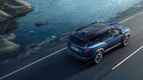 Vozilo Dacia Bigster u pokretu na cesti uz obalu, snimljeno iz ptičje perspektive







