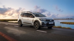 Vozilo Dacia Jogger u vožnji cestom uz obalu u večernjem ambijentu.