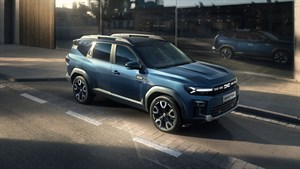 Vozilo Dacia Bigster u vožnji gradskom cestom ispred moderne zgrade.