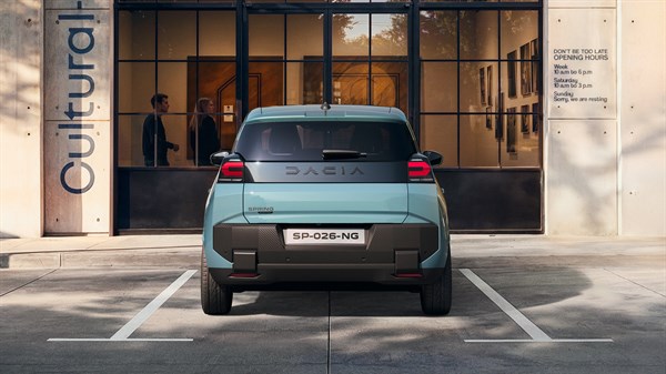 Dacia Spring vozilo u plavoj boji parkirano ispred moderne zgrade, pogled straga.