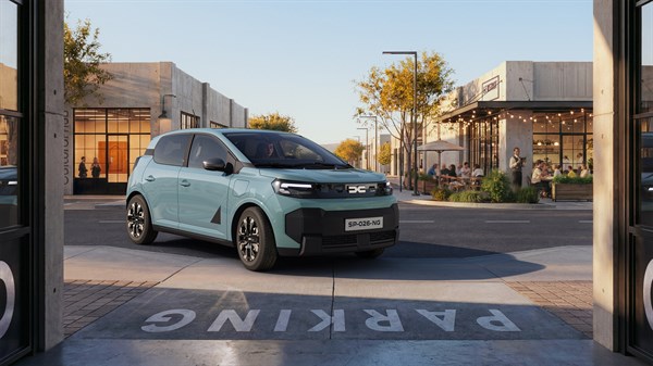 Dacia Spring u plavoj boji vozi se ulicom moderne urbane četvrti.