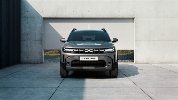 Vozilo Dacia Duster prikazano sprijeda, parkirano ispred moderne zgrade.