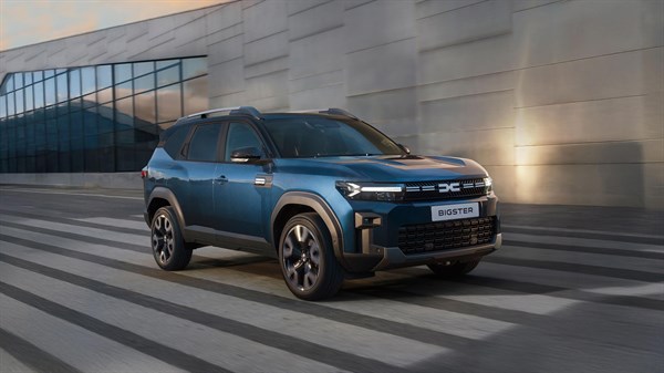 Vozilo Dacia Bigster u vožnji gradskom cestom ispred moderne zgrade.