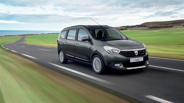 Sivi Dacia Lodgy u vožnji otvorenom cestom kroz prirodni krajolik