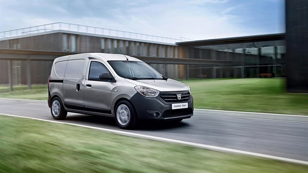 Dacia Dokker Van srebrne boje u vožnji pokraj poslovne zgrade.