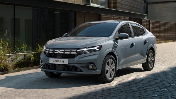 Dacia Logan sive boje parkiran ispred moderne stambene zgrade.
