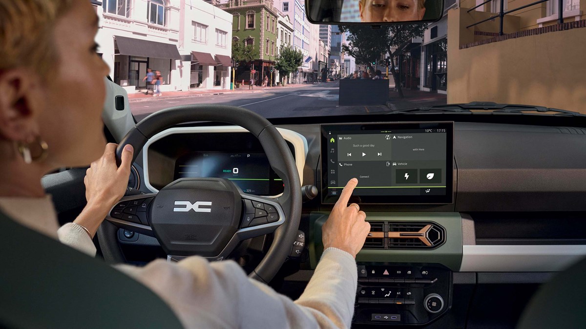 Vozačica u vozilu Dacia Spring koristi multimedijski sustav na središnjem zaslonu tijekom gradske vožnje.