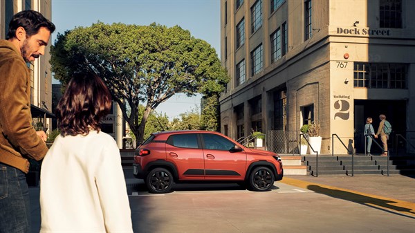 Dacia vozilo parkirano na gradskoj ulici, dok ga promatraju dvije osobe