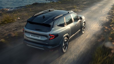 Dacia Bigster vozi makadamskom cestom uz obalu, snimljen iz gornjeg stražnjeg kuta.