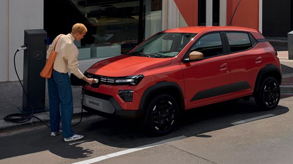 Dacia Spring priključen na javnu punionicu, dok vozač puni vozilo.