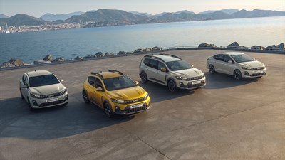 Četiri vozila Dacia parkirana uz obalu mora, s planinama u pozadini.