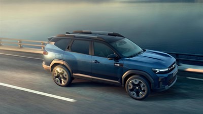 Plavi Dacia Bigster u vožnji cestom uz jezero