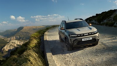 Sivi Dacia Duster na makadamskoj planinskoj cesti s pogledom na planinski krajolik