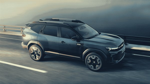 Tamno plavi Dacia Bigster u vožnji uz obalu, na cesti uz more