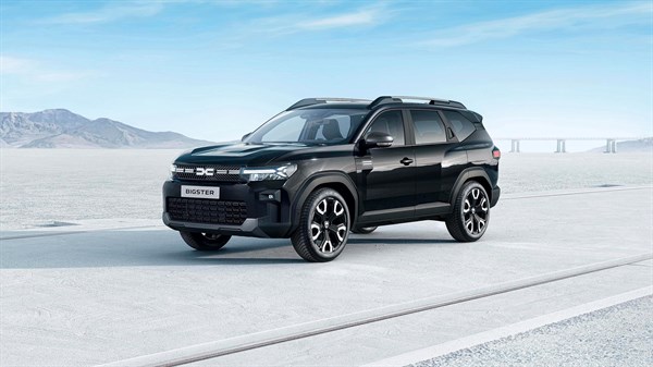 Crni Dacia Bigster na otvorenoj cesti, sa snježnim planinama i mostom u pozadini.