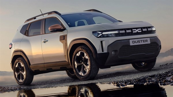 Bijeli Dacia Duster parkiran na kamenitoj obali iz prednjeg bočnog kuta.