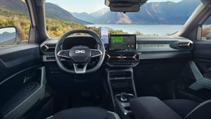 Unutrašnjost vozila Dacia Duster s prikazom upravljača i središnjeg zaslona, u pozadini se vidi planinski krajolik kroz vjetrobransko staklo.