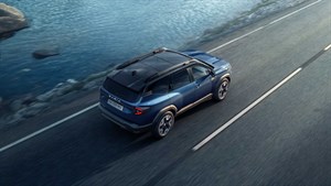 Moder SUV vozilo Dacia Bigster vozi po obalnoj cesti uz vodu. Vozilo je prikazano iz ptičje perspektive, u pokretu.

