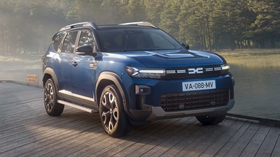 Vozilo Dacia Bigster parkirano na drvenoj platformi u prirodi.