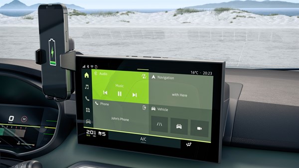 Pametni telefon postavljen na YouClip bežični punjač uz zaslon u vozilu Dacia Jogger.