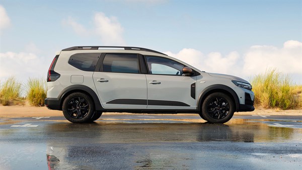 Vozilo Dacia Jogger snimljeno bočno pokraj vodene površine s travom u pozadini.