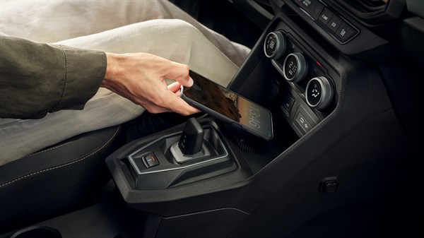 Unutrašnjost vozila Dacia Jogger s osobom koja odlaže pametni telefon na ugrađeni bežični punjač u središnjoj konzoli.