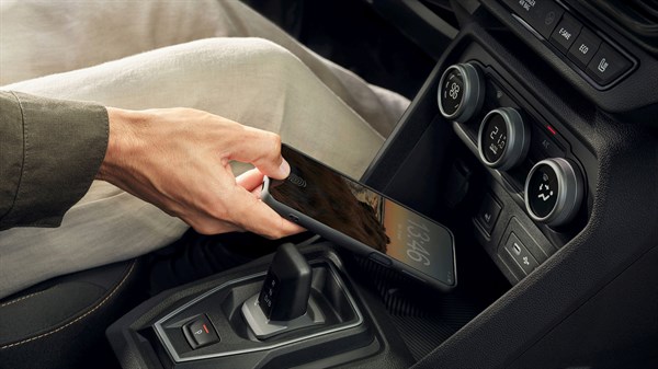 Ruka odlaže pametni telefon na ugrađeni bežični punjač u vozilu Dacia Jogger, smješten u središnjoj konzoli.