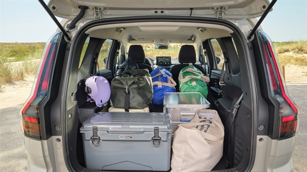 Otvoreni prtljažnik vozila Dacia Jogger s podignutim petim vratima, prepun putne opreme i torbi, uz pogled na kabinu i sklopiva stražnja sjedala.