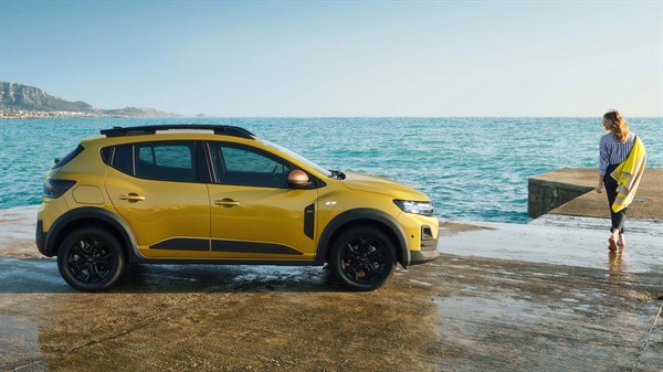 Vozilo Dacia Sandero Stepway parkirano uz more, pored osobe koja stoji na obali i gleda prema vodi.