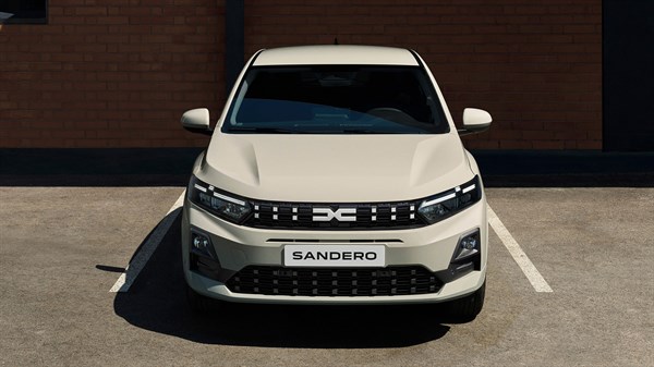 Prednji pogled na vozilo Dacia Sandero u bijeloj boji parkirano ispred zgrade.