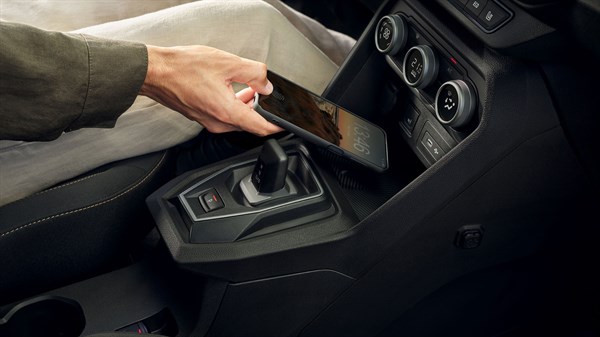 Ruka odlaže mobilni uređaj na ugrađeni induktivni bežični punjač u vozilu Dacia Jogger.