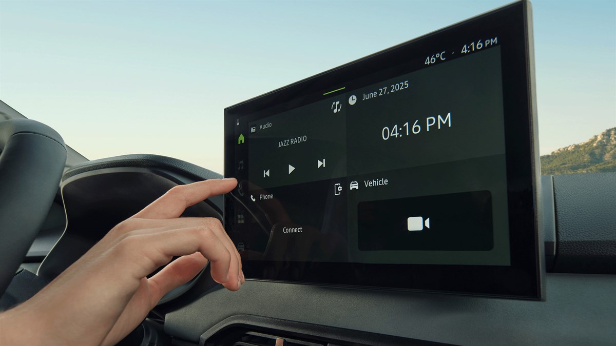 Ruka dodiruje multimedijski zaslon u vozilu Dacia Jogger na kojem je prikazano sučelje s radiom, telefonom i postavkama vozila.