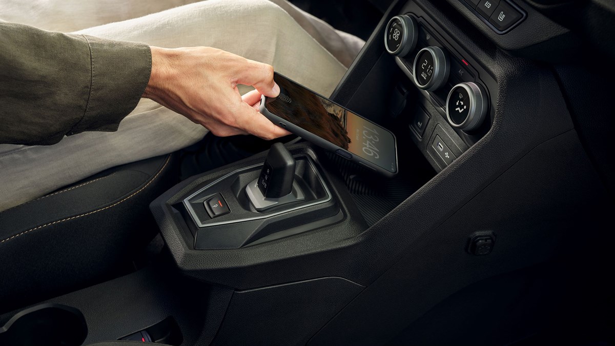 Ruka odlaže pametni telefon na induktivni bežični punjač u središnjoj konzoli vozila Dacia Jogger.
