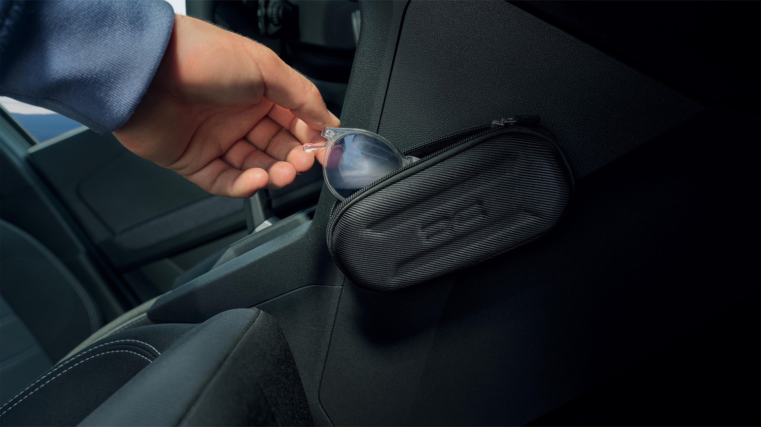 Ruka koja odlaže sunčane naočale u YouClip etui pričvršćen na unutrašnjost vozila Dacia Sandero.