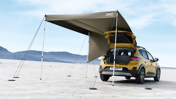 Vozilo Dacia Sandero Stepway parkirano u pustom krajoliku s podignutim stražnjim vratima, uz postavljenu InNature krovnu nadstrešnicu koja stvara zasjenjeni vanjski prostor.