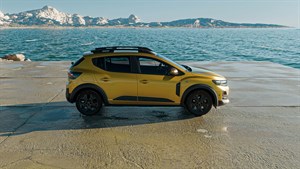 Žuto vozilo Dacia Sandero prikazano sa stražnje strane pored mora.