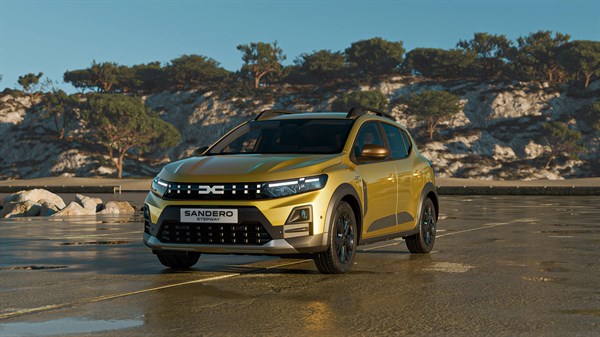 Vozilo Dacia Sandero u žutoj boji snimljeno sprijeda na sunčanom obalnom području, s kamenitim krajolikom u pozadini.