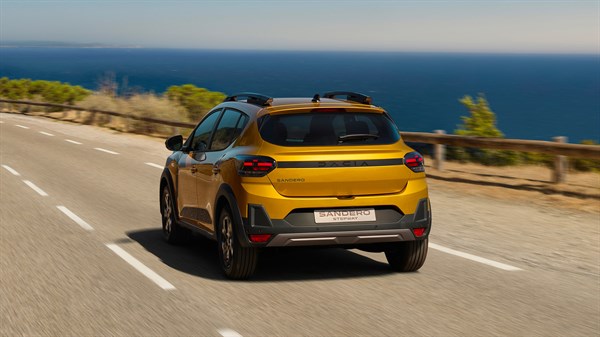 Vozilo Dacia Sandero Stepway snimljeno straga u vožnji uz obalnu cestu, s pogledom na more u pozadini.