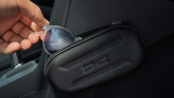 Unutrašnjost vozila Dacia Sandero Stepway s prikazom ruke koja sprema sunčane naočale u pretinac za pohranu uz sjedalo.