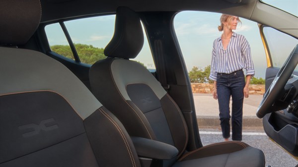 Unutrašnjost vozila Dacia Sandero Stepway s perivim Microcloud presvlakama, snimljena prema prednjim sjedalima i otvorenim vratima.