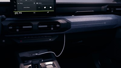 Unutrašnjost vozila Dacia Striker s prikazom diskretnog otvora za provlačenje kabela za punjenje pametnog telefona.