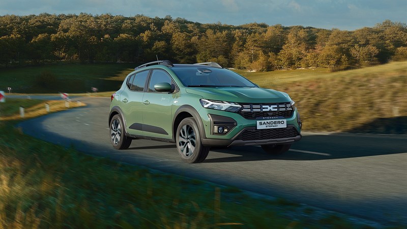 Zeleno vozilo Sandero Stepway prikazano s prednje strane na cesti, okruženo drvećem i prirodom.